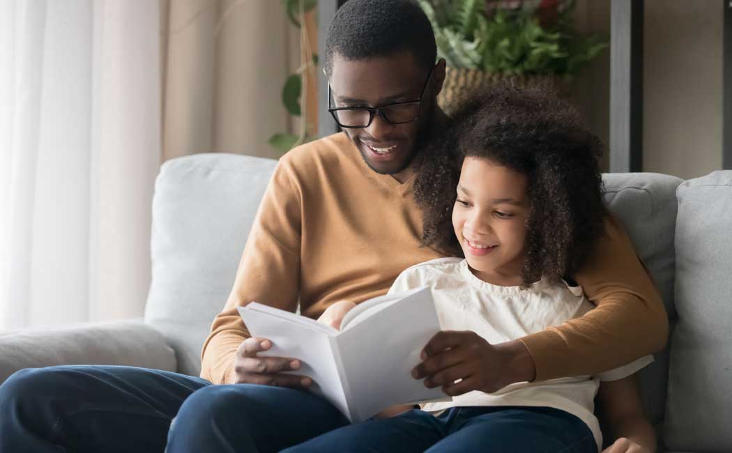 Father reading book to daughter 