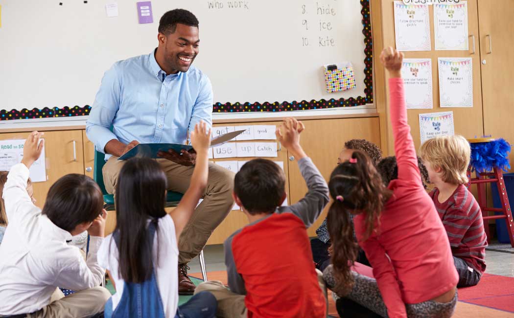 Elementary school kids sitting around teacher in a classroom 