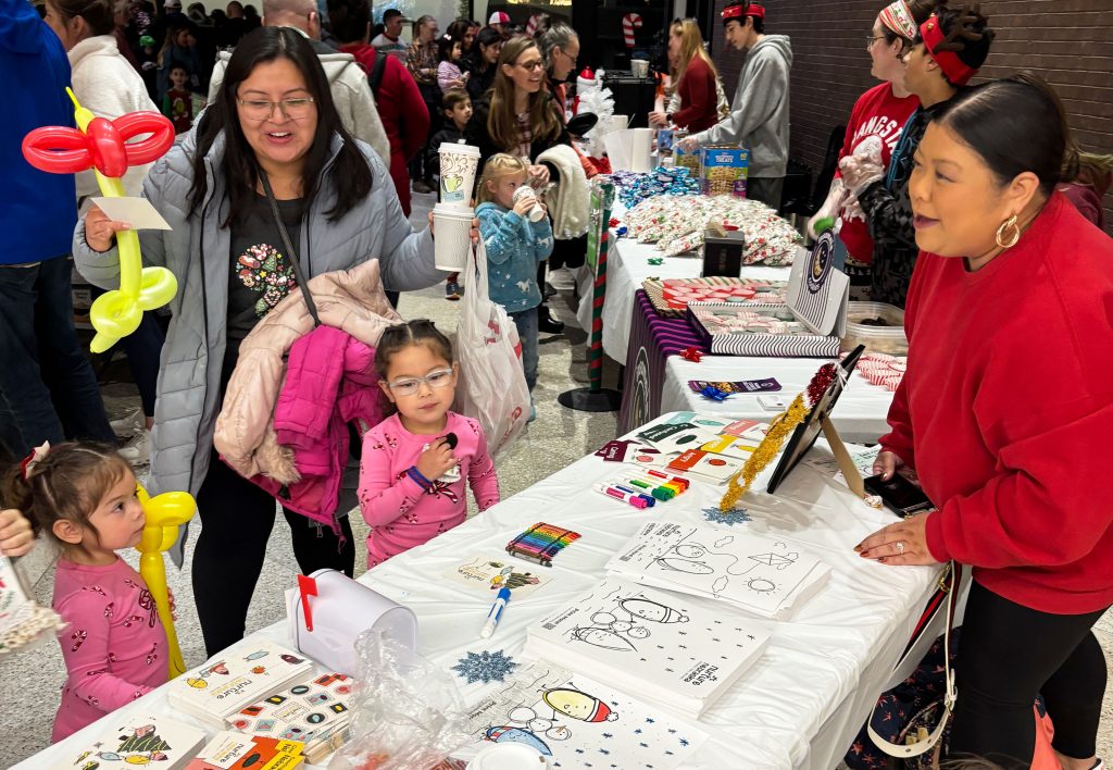Jemalyn Griffin (right), associate professor of practice in advertising and public relations at the University of Nebraska–Lincoln, talks with a family about Nurture Nebraska at the Lincoln Airport's LNK Santa Bash community event Dec. 5, 2025.