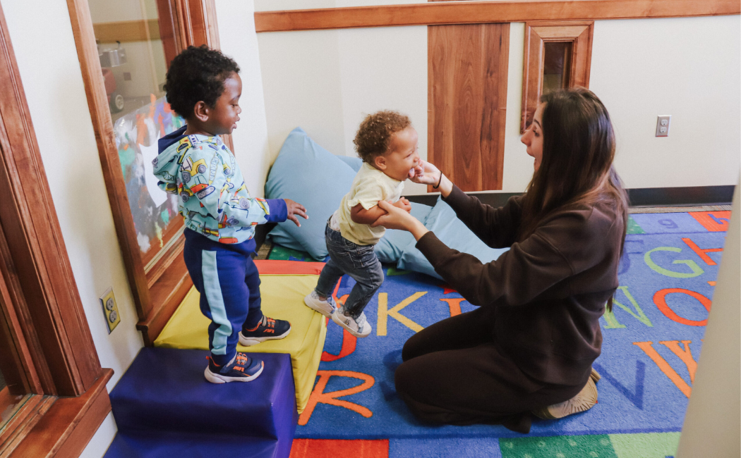 Early childhood teacher plays with two toddlers.