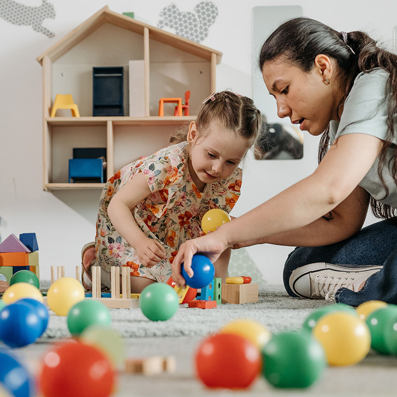 Woman and young girl playing with brightly colored balls.