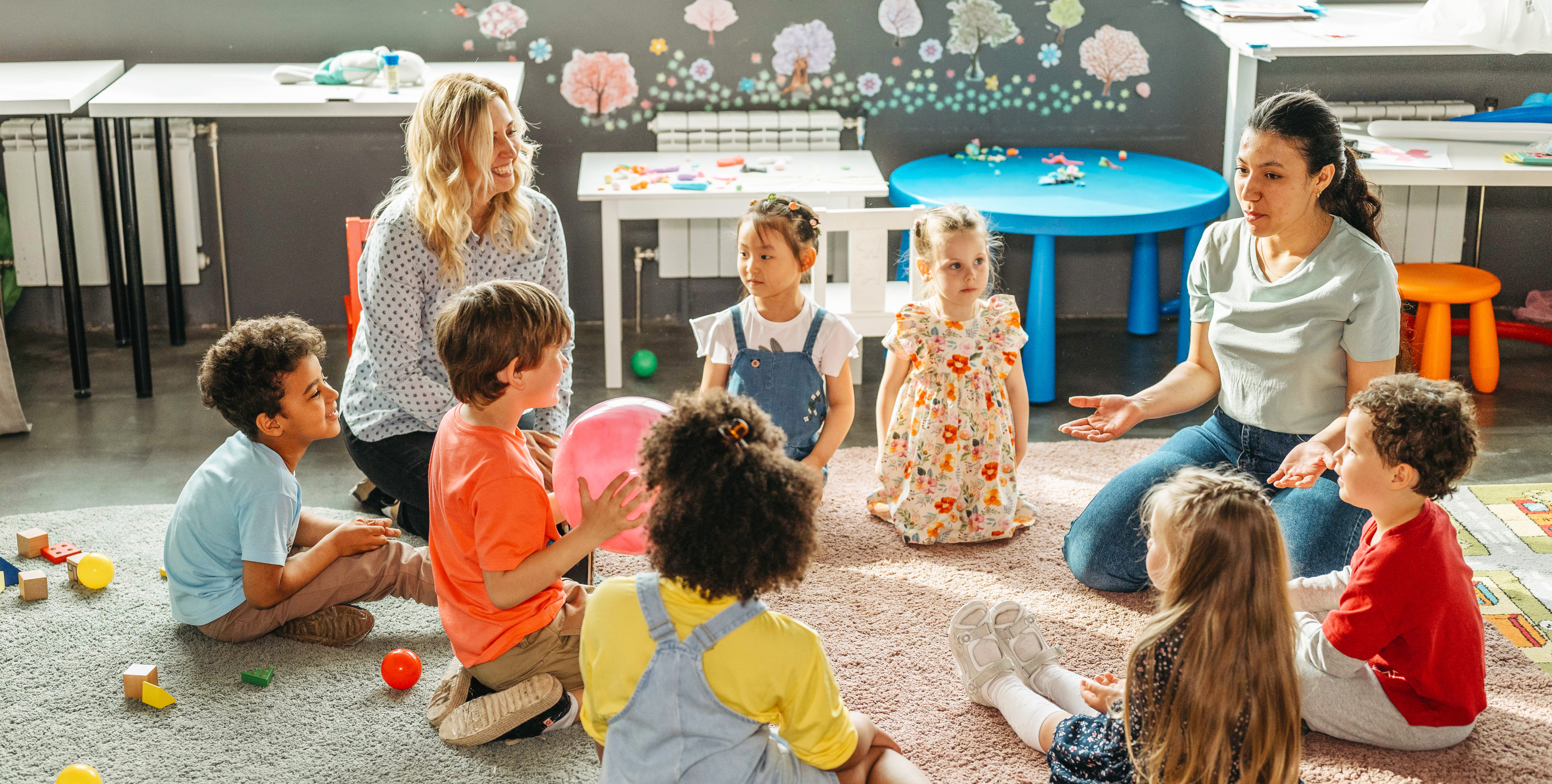 Female teacher drawing with three preschool boys.
